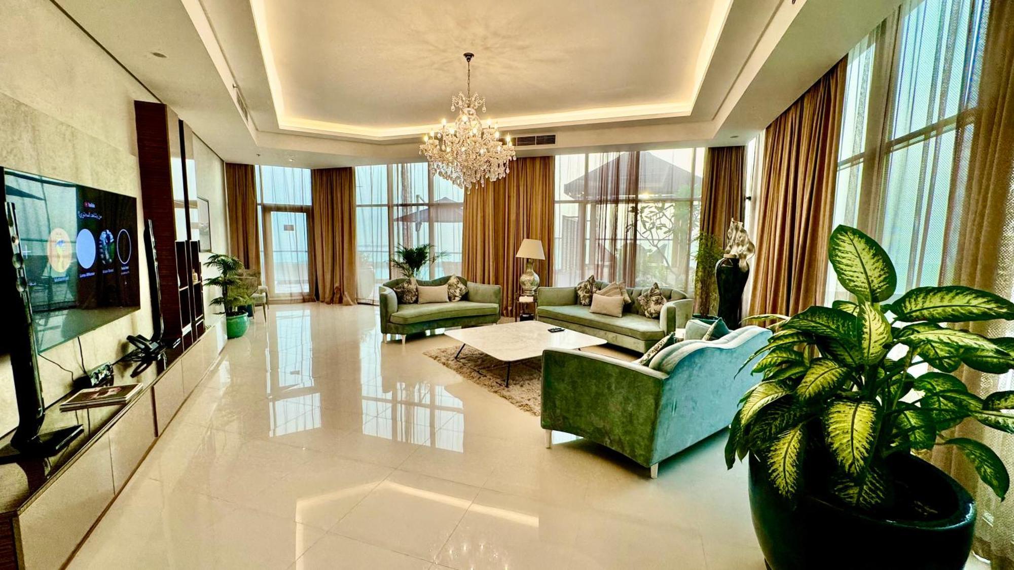 Lagoona Beach Luxury Resort And Spa Манама Экстерьер фото The photo depicts a spacious and elegantly designed living room. The room features large windows allowing natural light to flood in, accompanied by sumptuous curtains. The furniture includes a pair of soft green sofas and a centerpiece coffee table s