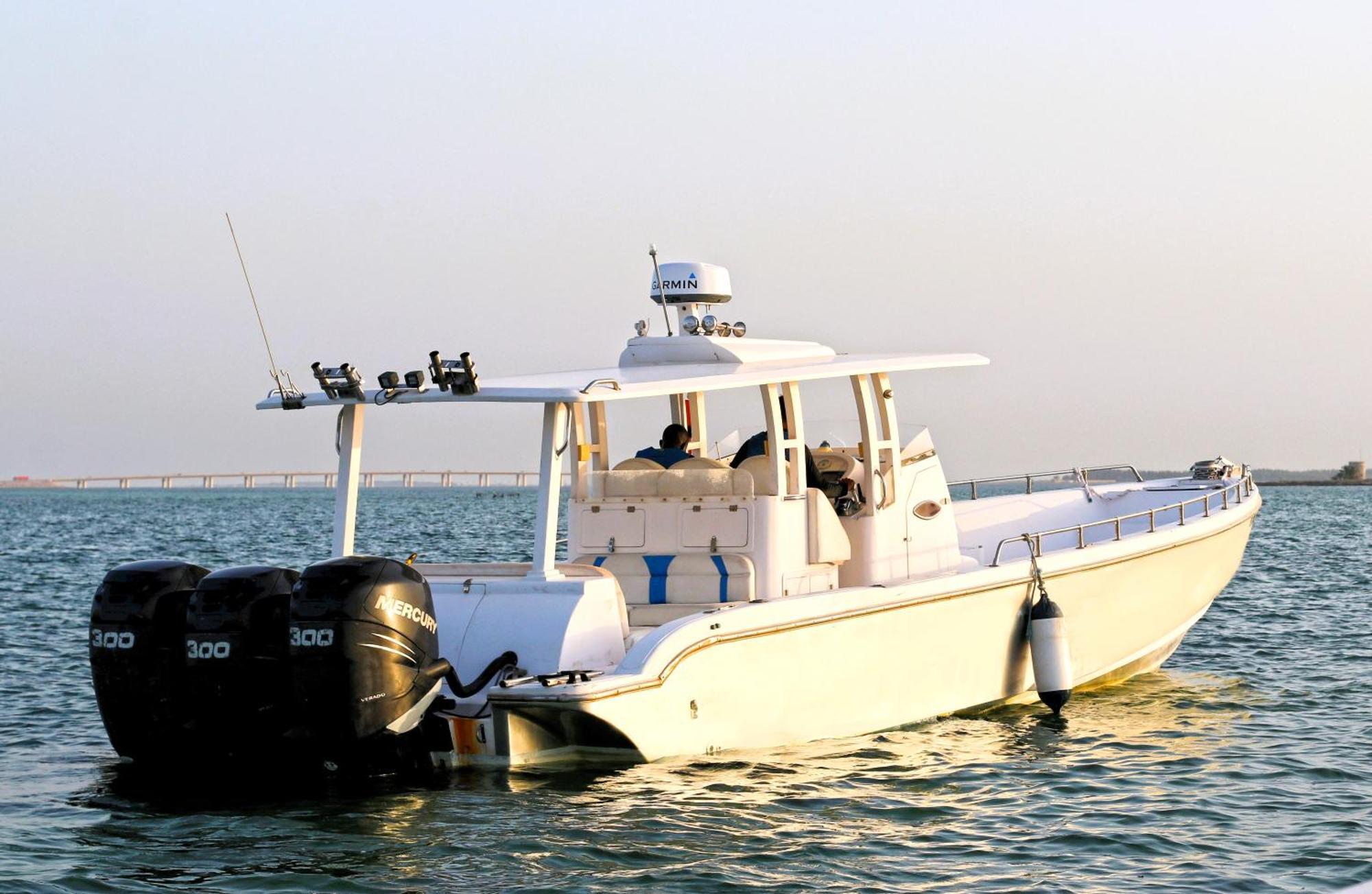 Lagoona Beach Luxury Resort And Spa Манама Экстерьер фото The photo shows a large, white motorboat equipped with three powerful outboard engines at the stern. The boat has a sleek design, with a spacious open deck and a covered cabin area that likely provides shelter and controls for navigation. The scene i