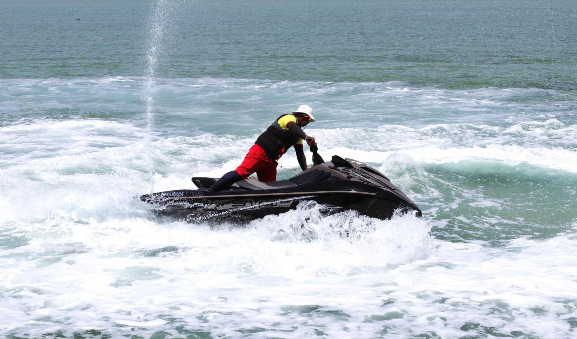 Lagoona Beach Luxury Resort And Spa Манама Экстерьер фото The photo shows a person riding a jet ski on the water. The rider is positioned upright, leaning forward with one hand on the handlebars, while the jet ski creates splashes of white foam around it. The water appears choppy, likely due to the motion o