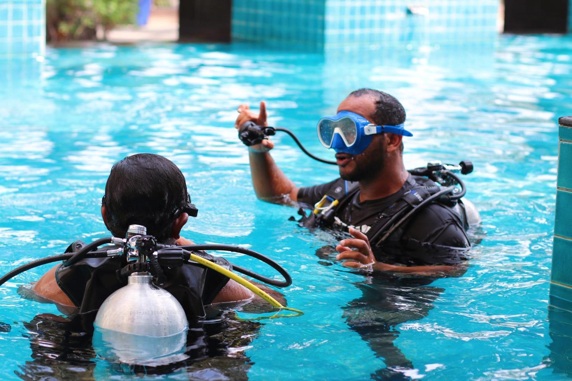 Lagoona Beach Luxury Resort And Spa Манама Экстерьер фото The photo shows two divers in a pool. One diver is wearing a scuba mask and is speaking to the other diver, who is also equipped with scuba gear. They appear to be engaged in a discussion, possibly related to diving instructions or safety. The water 