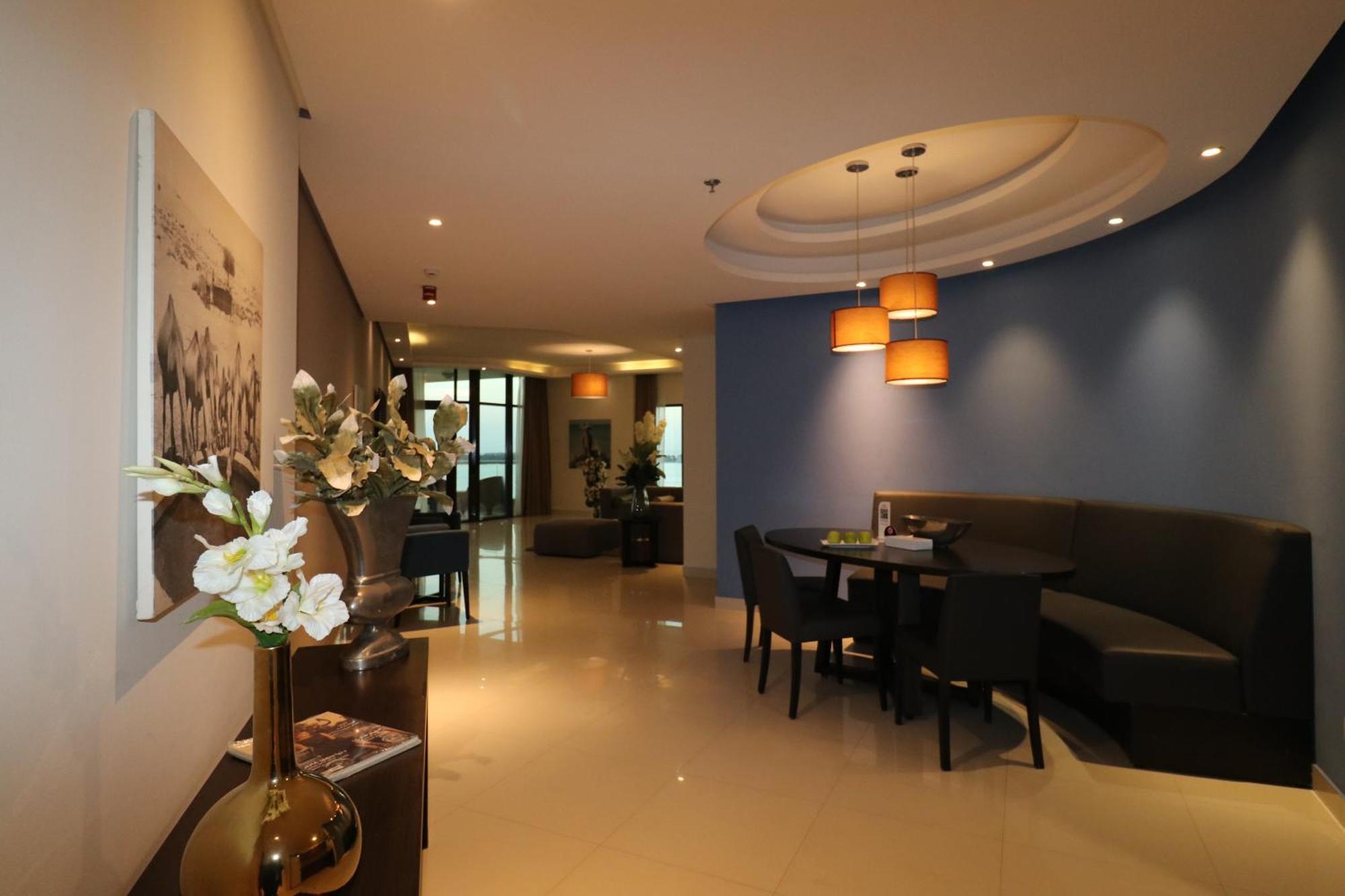 Lagoona Beach Luxury Resort And Spa Манама Экстерьер фото The photo showcases an interior space, likely a modern lounge or reception area. It features a combination of soft lighting, neutral-colored walls, and decorative elements. There are elegant light fixtures hanging from the ceiling, and a curved blue 